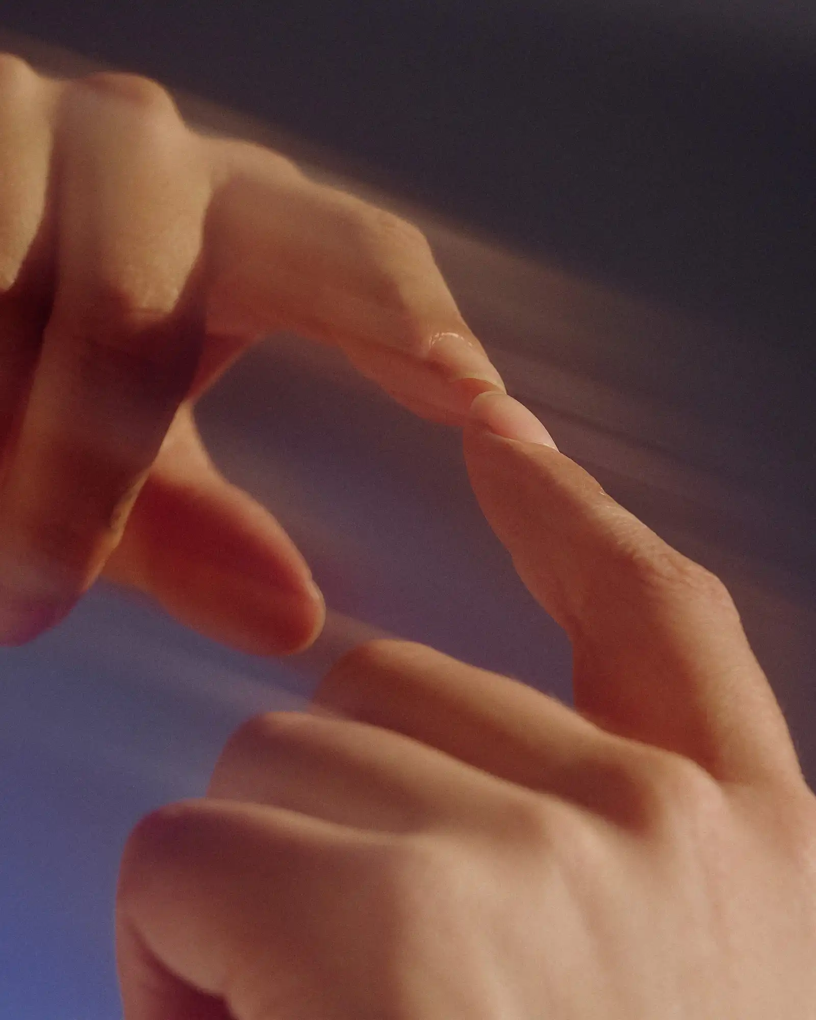 Two hands reaching toward each other, fingertips touching